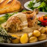 Plate of Creamy Tuscan Chicken served with garlic mashed potatoes, roasted broccoli, and a side salad.